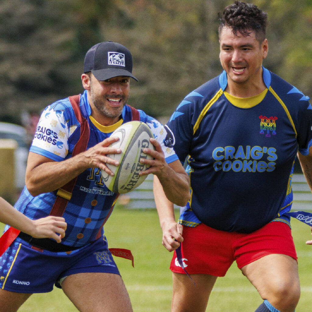 Two smiling Muddy York players playing flag rugby at Beaver Bowl.