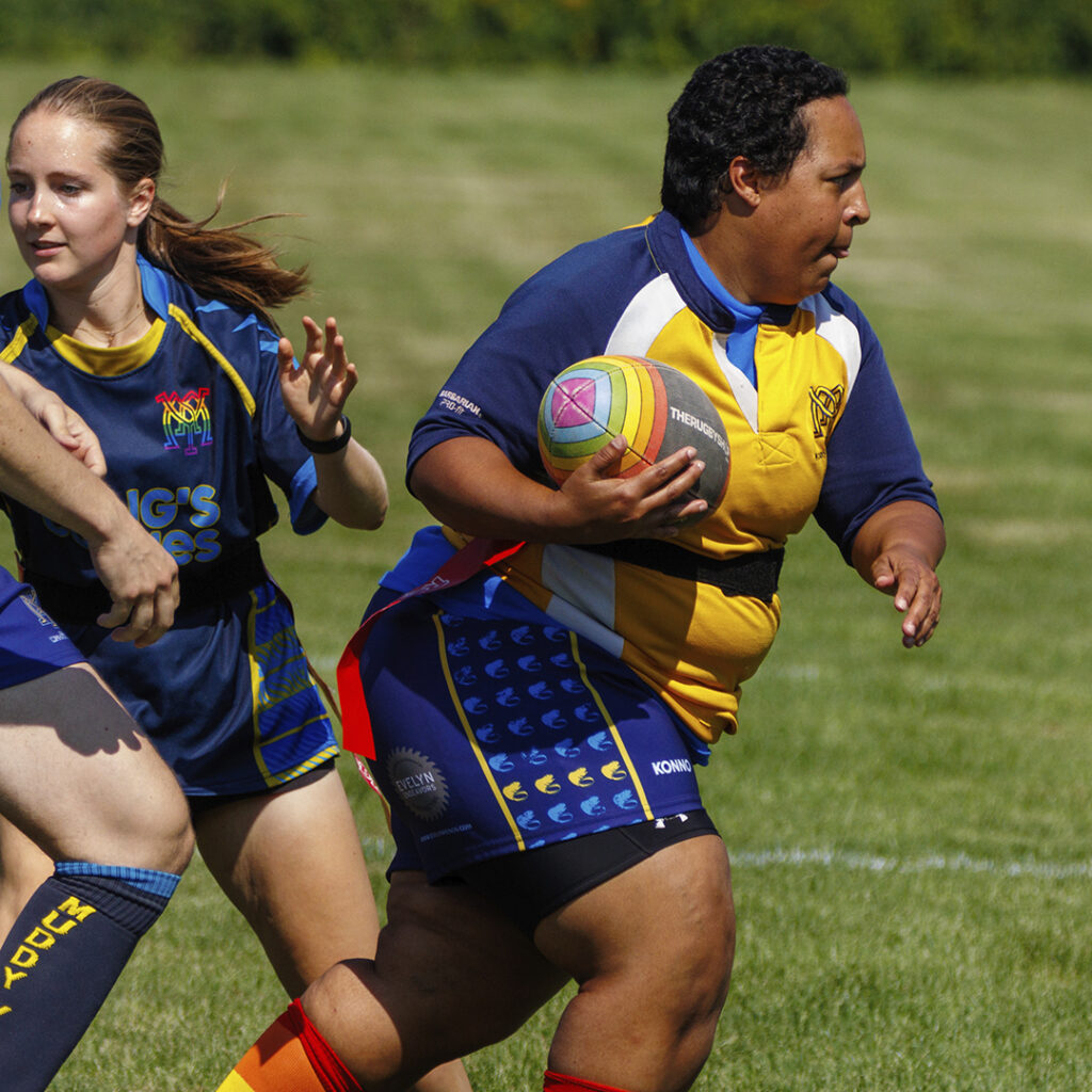 Muddy York player running with the ball. She's broken through the defenders, flags unpulled.